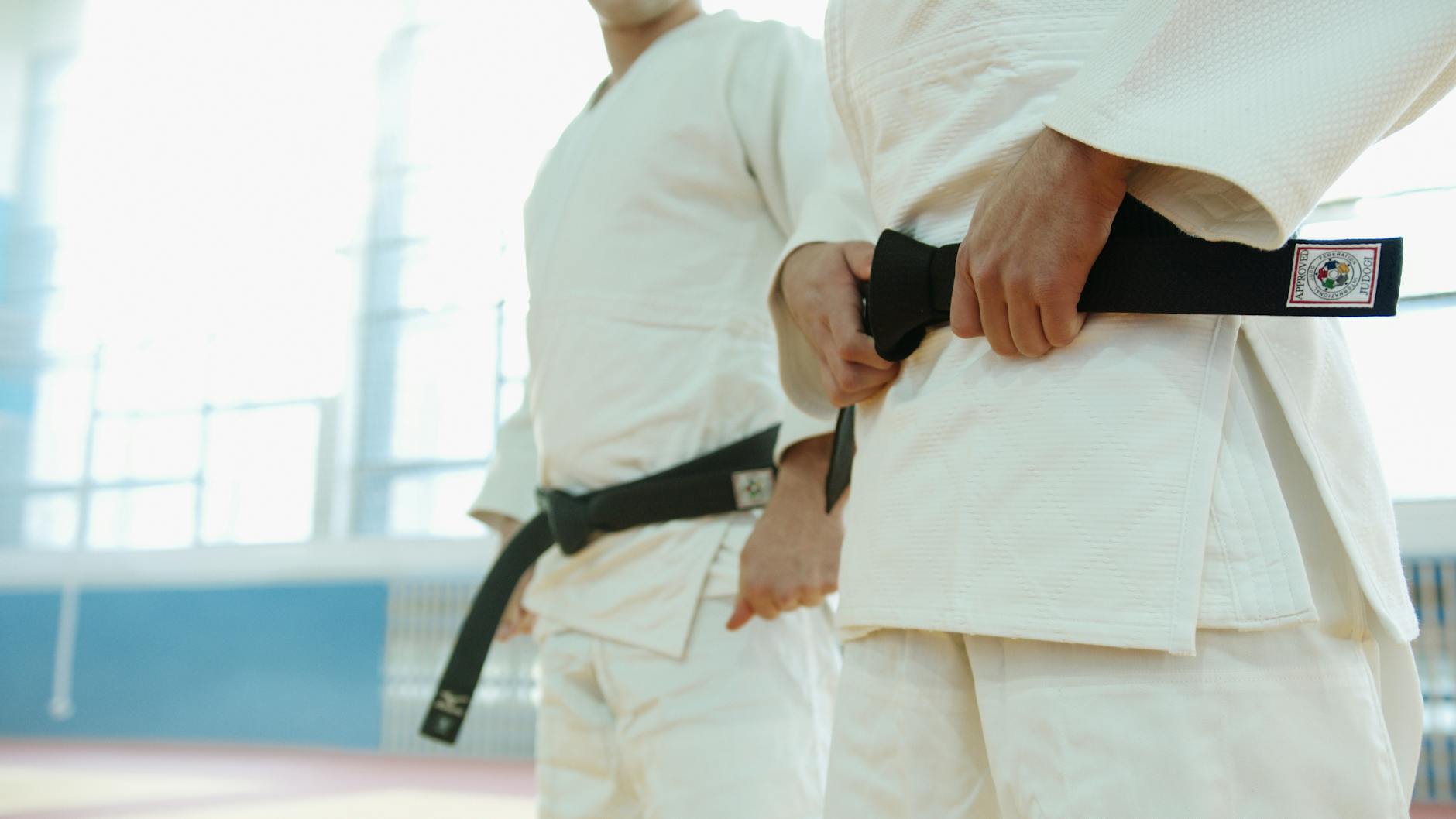 close up shot of two people wearing karategi and black belt